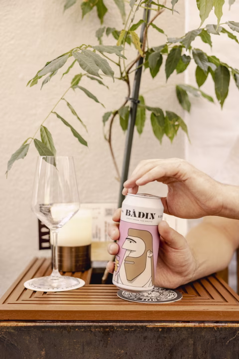 a hand opening a can of craft beer on a small wooden table